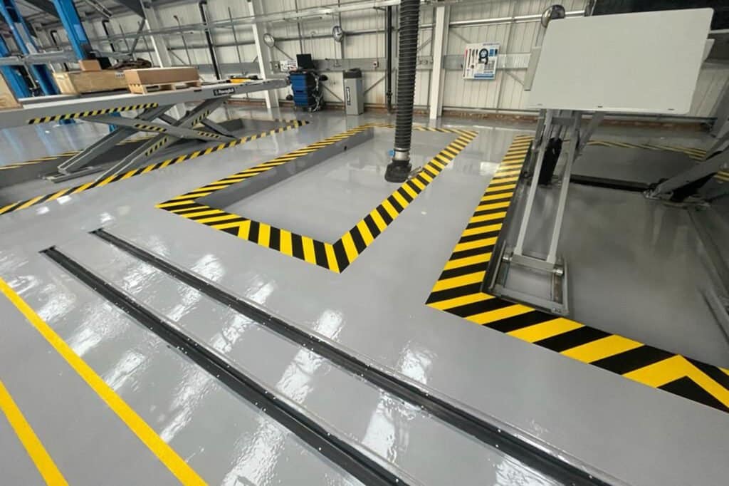Freshly installed yellow and black resin line marking at an mot test centre in northampton.