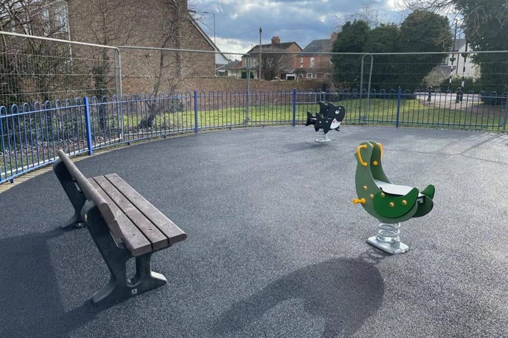 Detail of finished play safe surface at a circular play area in bedfordshire, showing bench and play equipment