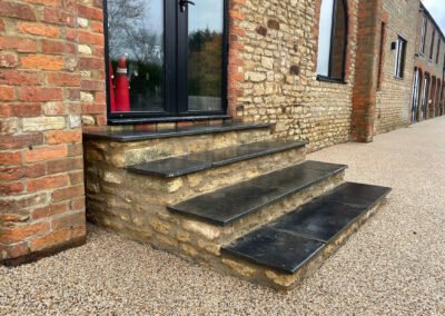 Finished detail showing driveway meeting a set of stone steps at a large resin bound driveway install in northamptonshire