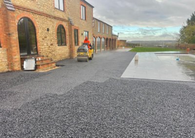 A permeable tarmac base is flattened with a twin drum roller, prior to the resin bound installation