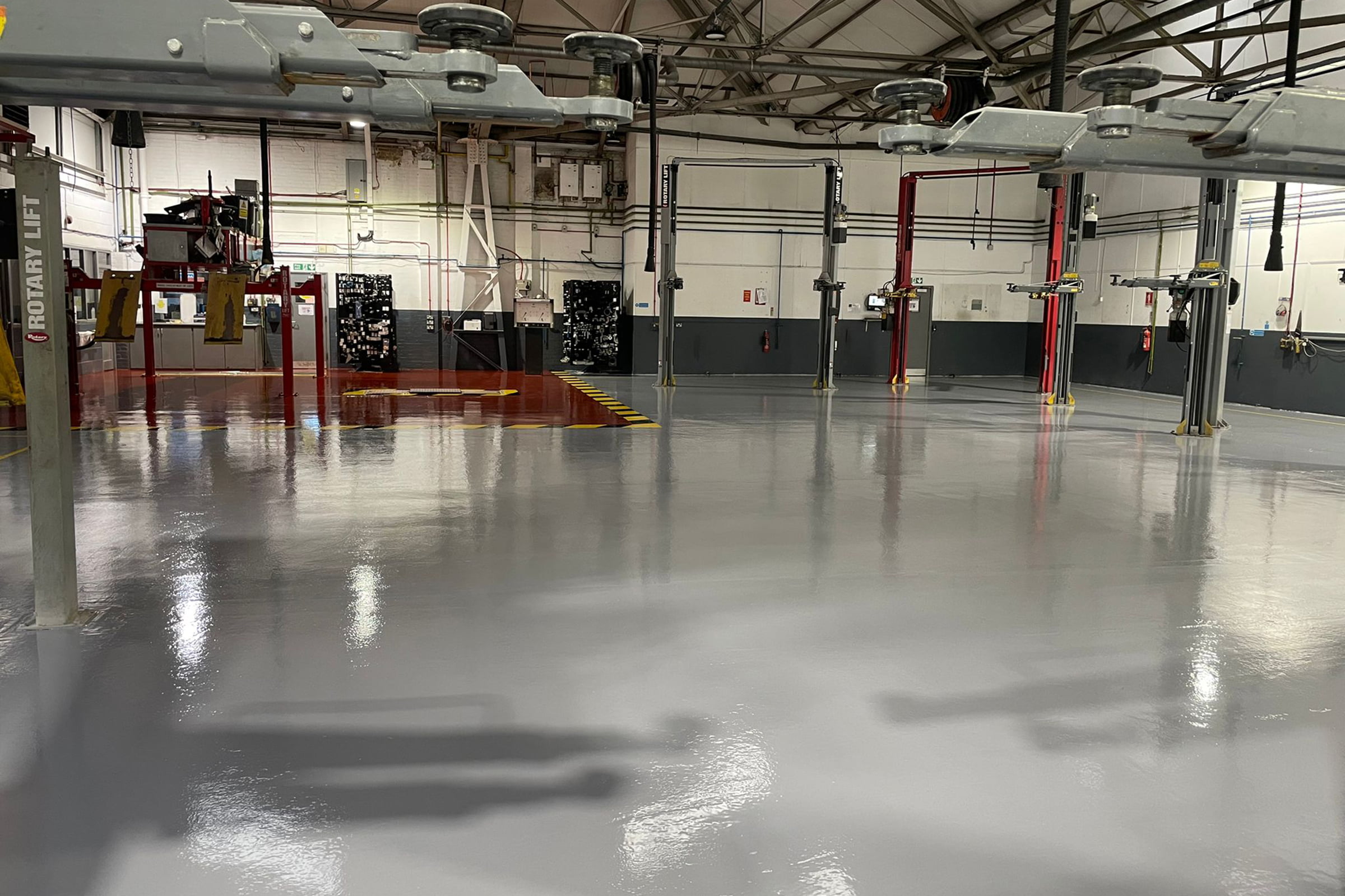Finished garage workshop floor, using epoxy resin. Red for the majority of the surface and red for the MOT bay