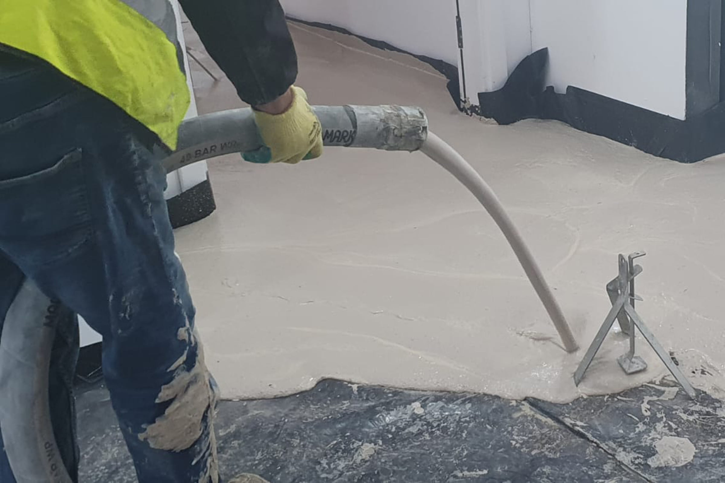 Screed contractors installing liquid screed poured directly from a large cement mixer truck for new warehouse flooring