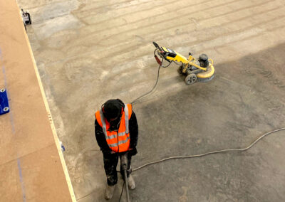 Floor screed contractor using a grinder to prepare a concrete floor