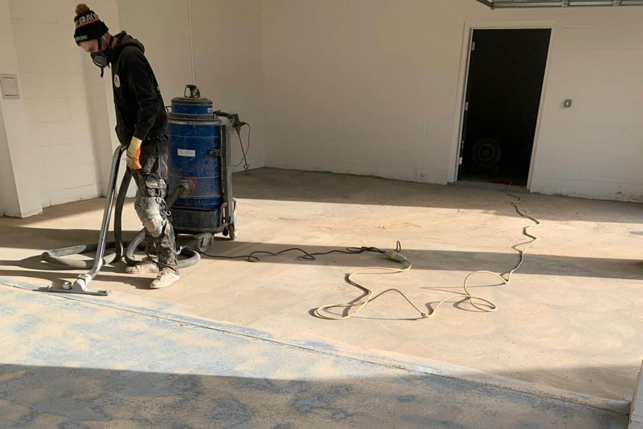 Worker using industrial vacuum after gargae floor preparation