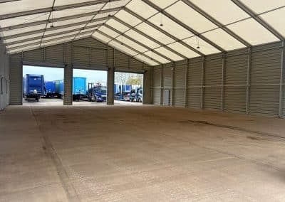 Empty storage area concrete flooring and trucks outside