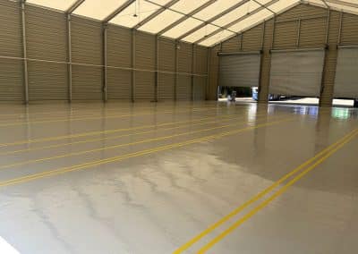 Shiny, empty warehouse with grey epoxy resin flooring and yellow lines