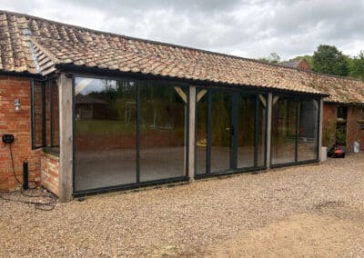 Modern glass-walled structure on old barn with gravel outside