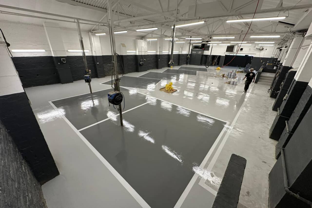 Clean, shiny workshop with several shades of grey epoxy flooring, with white line marking
