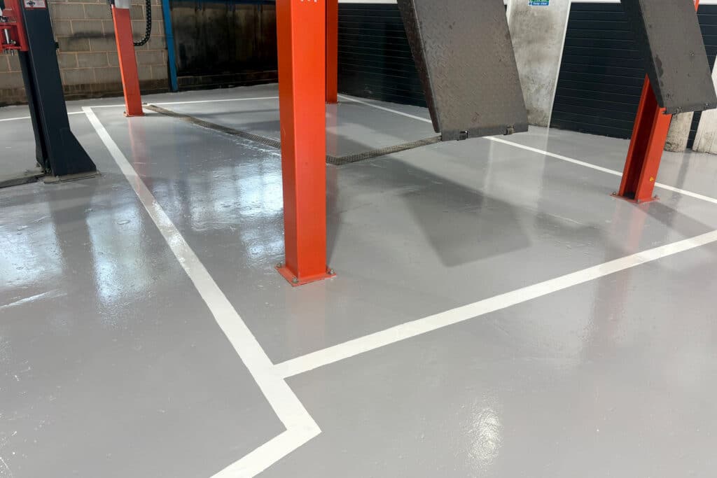 Clean, grey epoxy resin commercial garage floor with red line markings
