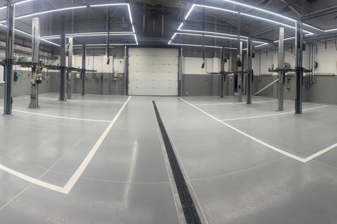 Empty EV workshop with grey epoxy flooring and white line markings